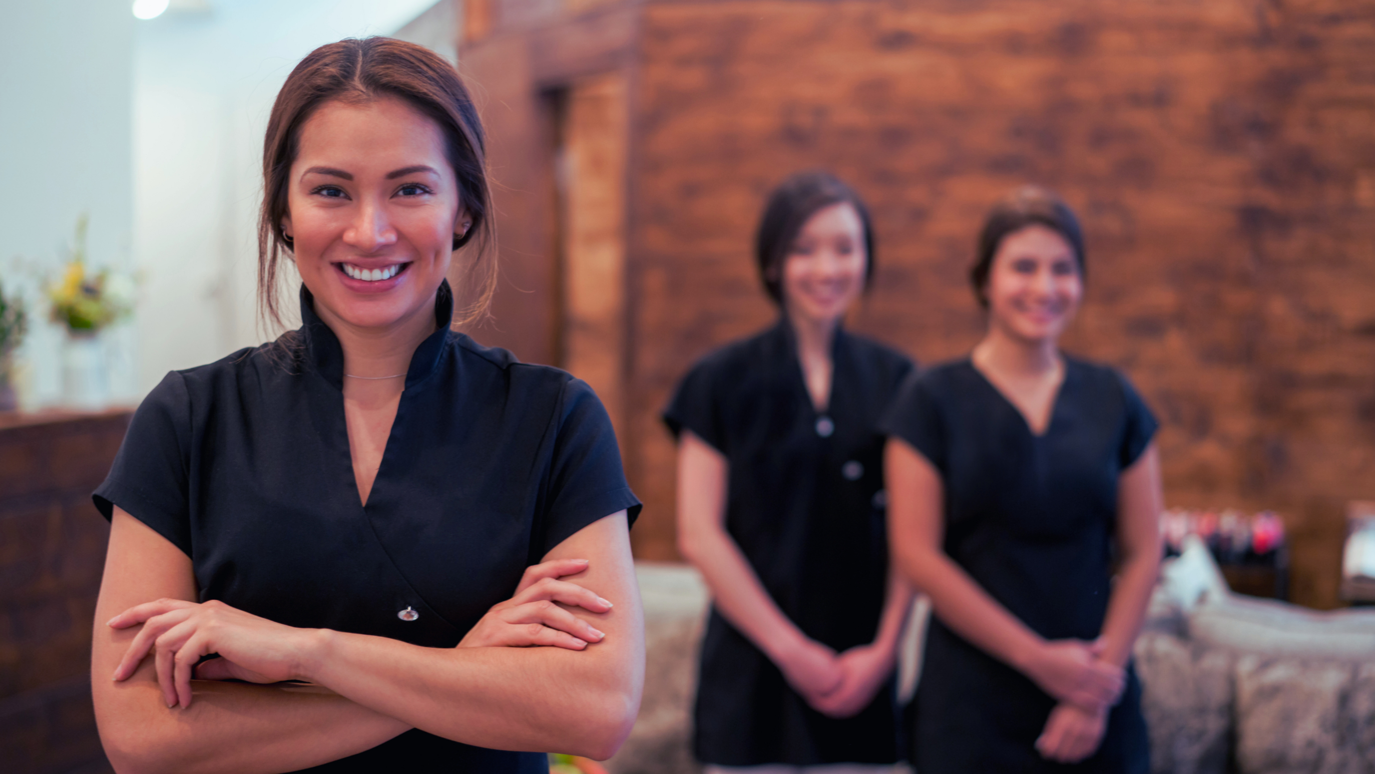 Team of happy workers that are wearing scrubs in a professional medical setting.