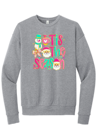 Tis the Season Snowman crewneck sweatshirt in Athletic Heather, featuring pink and teal TIS THE SEASON letters with a snowman, a cocoa mug, and Santas
