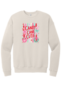 Candy Cane Cutie crewneck sweatshirt in Heather Dust, featuring red CANDY CANE CUTIE letters on pastel stripes with candy canes, cocoa, and bows