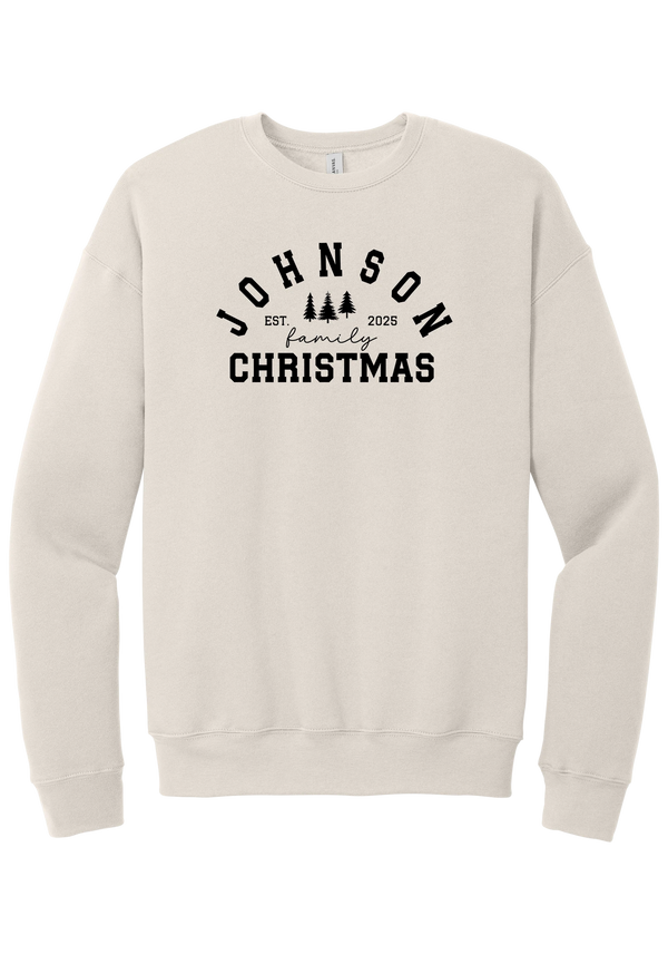 Personalized Family Christmas crewneck sweatshirt in Heather Dust, featuring an arched family name over pine trees with EST. year and family Christmas lettering