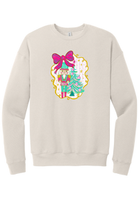Nutcracker Bow crewneck sweatshirt in Heather Dust, featuring a teal and pink nutcracker beside a tinsel tree under a big hot pink bow