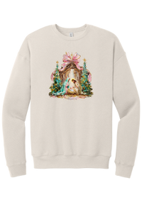 Painterly Nativity crewneck sweatshirt in Heather Dust, featuring a painterly nativity scene with Mary, Joseph, and baby Jesus in a wooden stable between teal Christmas trees and a pink bow