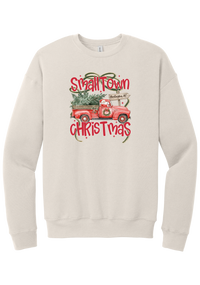 Personalized Small Town Christmas crewneck sweatshirt in Heather Dust, featuring Santa in a vintage red pickup truck hauling a Christmas tree past a personalized town road sign, with red Small Town Christmas lettering