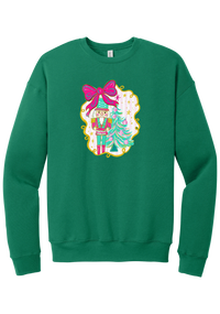 Nutcracker Bow crewneck sweatshirt in Kelly Green, featuring a teal and pink nutcracker beside a tinsel tree under a big hot pink bow