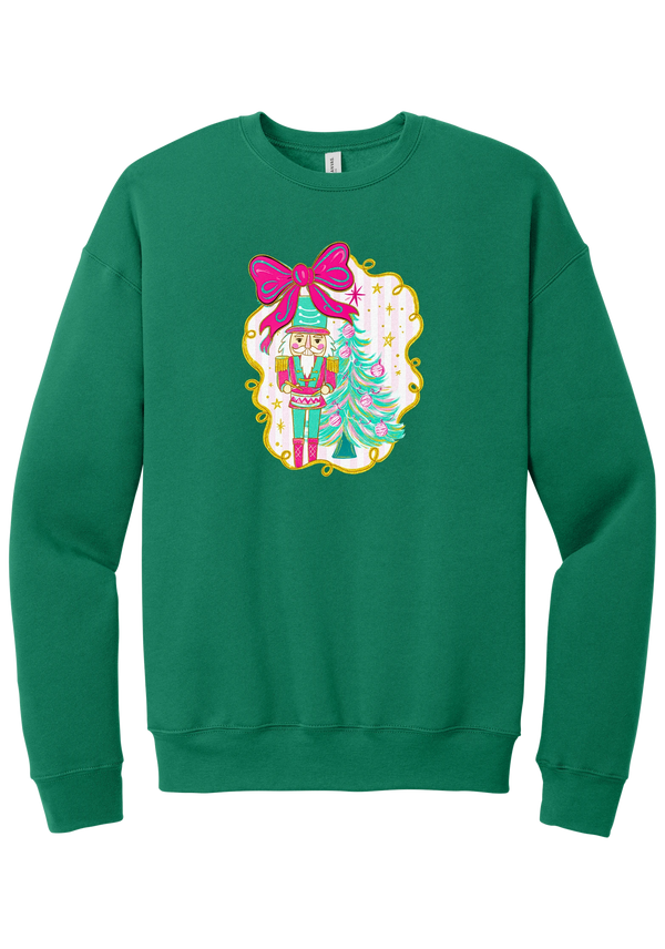 Nutcracker Bow crewneck sweatshirt in Kelly Green, featuring a teal and pink nutcracker beside a tinsel tree under a big hot pink bow