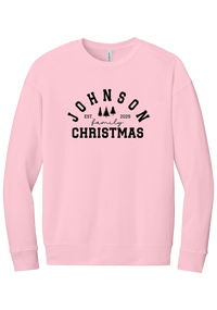 Personalized Family Christmas crewneck sweatshirt in Pink, featuring an arched family name over pine trees with EST. year and family Christmas lettering