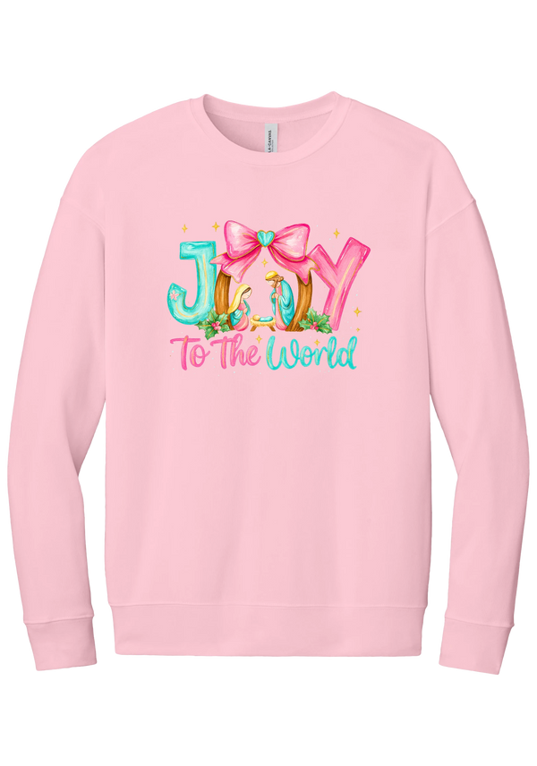 Joy to the World Nativity crewneck sweatshirt in Pink, featuring painted JOY letters framing a nativity scene with a pink bow and To The World script