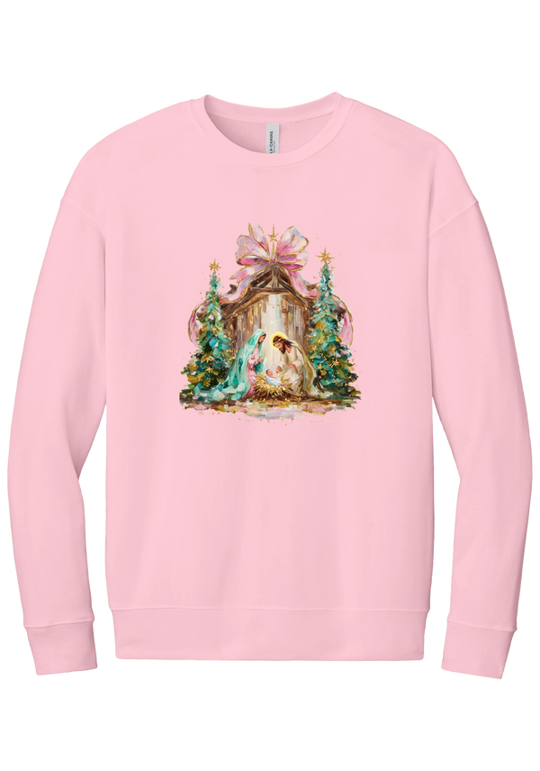 Painterly Nativity crewneck sweatshirt in Pink, featuring a painterly nativity scene with Mary, Joseph, and baby Jesus in a wooden stable between teal Christmas trees and a pink bow