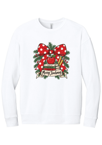 Merry Teachmas crewneck sweatshirt in White, featuring a red polka dot bow over a stack of books reading Teach, Inspire, Change with an apple, pencils, evergreen, and a Merry Teachmas banner