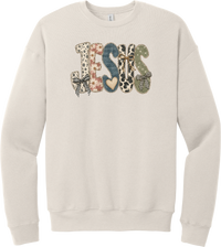 Jesus Patchwork crewneck sweatshirt in Heather Dust, featuring JESUS in patchwork letters of floral, leopard, denim, and cow print with gingham bows and a heart