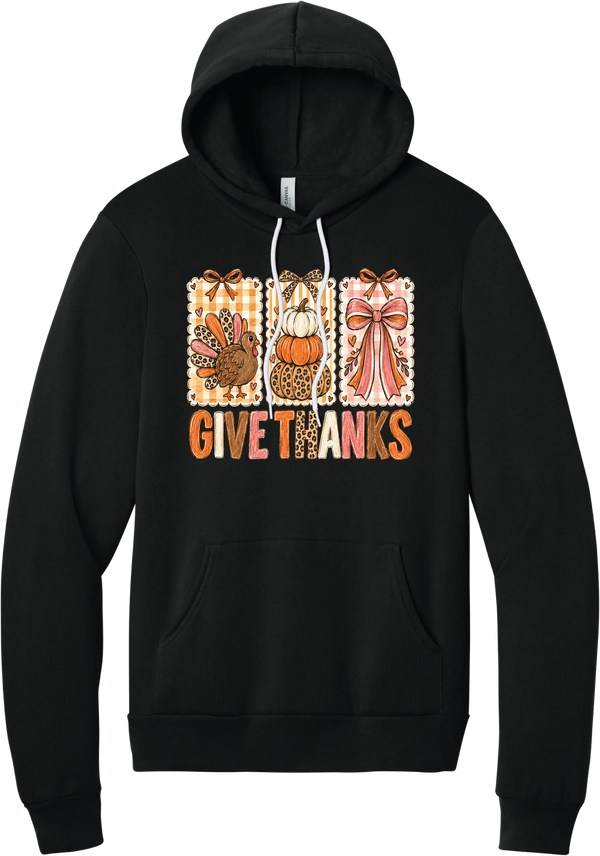 Give Thanks Coquette hoodie in Black, featuring three bow-topped stamp panels with a turkey, stacked pumpkins, and a pink bow above Give Thanks in patchwork letters