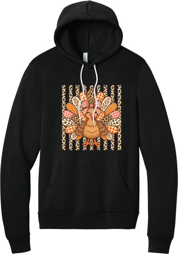Preppy Turkey hoodie in Black, featuring a smiling turkey with gingham and leopard feathers and a pink bow on a leopard stripe background