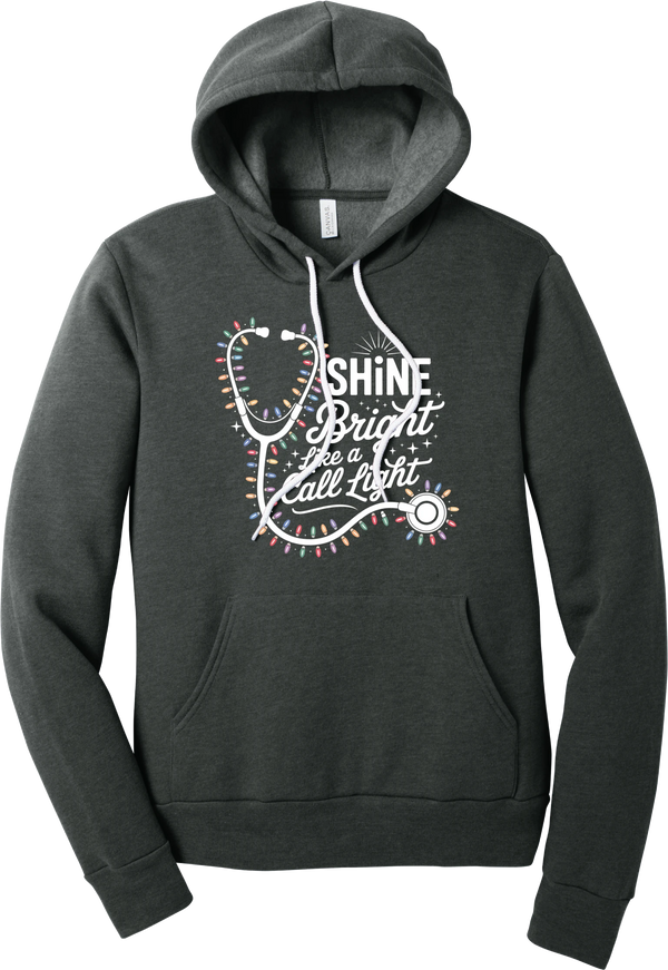 Shine Bright Like a Call Light hoodie in Dark Grey Heather, featuring a white stethoscope wrapped in multicolor Christmas lights with Shine Bright Like a Call Light lettering and sparkles