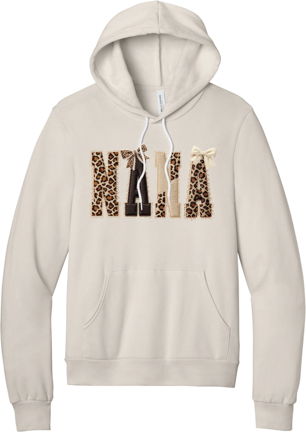Grandma Leopard Applique hoodie in Heather Dust, featuring NANA spelled out in leopard, cream, and chocolate patches with a scalloped stitched applique look and two bows