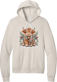 Highland Holidays hoodie in Heather Dust, featuring a fluffy baby Highland cow in a Fair Isle knit scarf, surrounded by frosted eucalyptus, pine, red berries, and white Christmas roses