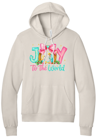 Joy to the World Nativity hoodie in Heather Dust, featuring painted JOY letters framing a nativity scene with a pink bow and To The World script