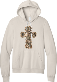 Quilted Patchwork Cross hoodie in Heather Dust, featuring a patchwork cross in camo, leopard, checkerboard, polka dot, and stripes with a fringed edge