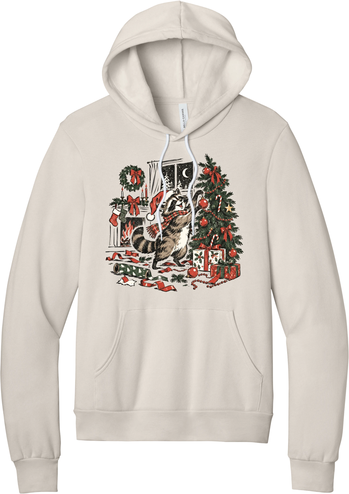 Raccoon Christmas hoodie in Heather Dust, featuring a vintage-style raccoon in a Santa hat and plaid scarf decorating a Christmas tree by the fireplace with ribbon and gifts scattered around