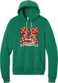 Merry Teachmas hoodie in Kelly Green, featuring a red polka dot bow over a stack of books reading Teach, Inspire, Change with an apple, pencils, evergreen, and a Merry Teachmas banner