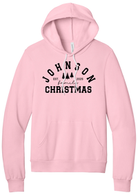 Personalized Family Christmas hoodie in Pink, featuring an arched family name over pine trees with EST. year and family Christmas lettering