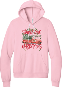 Personalized Small Town Christmas hoodie in Pink, featuring Santa in a vintage red pickup truck hauling a Christmas tree past a personalized town road sign, with red Small Town Christmas lettering