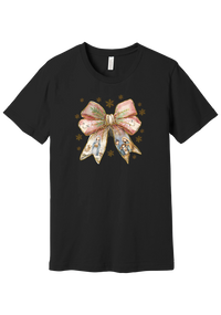 Nativity Bow tee in Black, featuring a blush satin bow with painted nativity scenes in its ribbons and gold snowflakes