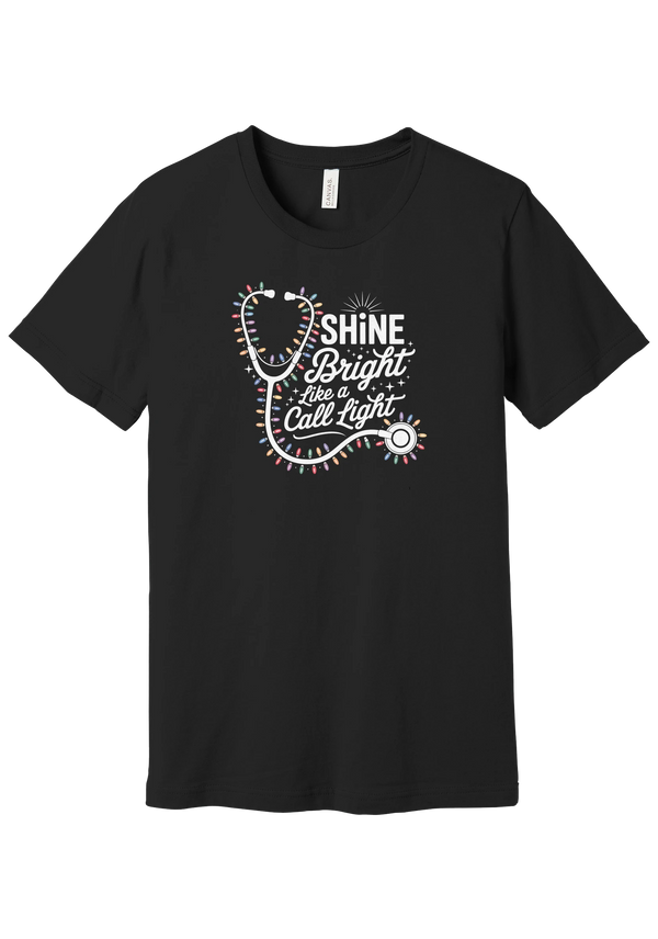 Shine Bright Like a Call Light tee in Black, featuring a white stethoscope wrapped in multicolor Christmas lights with bold Shine Bright Like a Call Light lettering