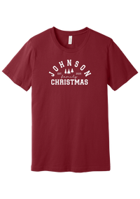 Personalized Family Christmas tee in Cardinal, featuring a personalized family last name arched over three pine trees with EST. and the year