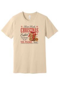 Farm Fresh Christmas Cookies tee in Soft Cream, featuring a vintage farmhouse bakery sign with a stack of Christmas cookies tied in a red ribbon bow
