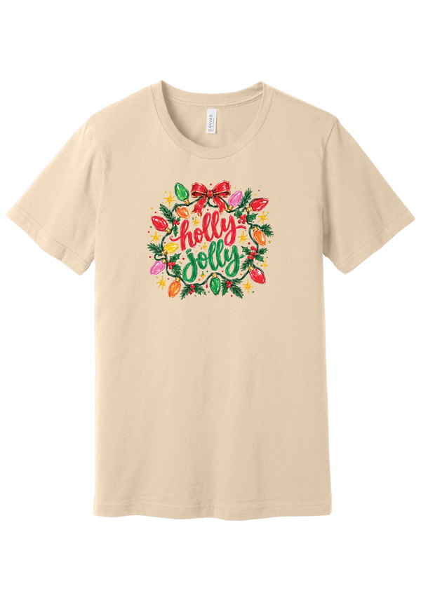 Holly Jolly Christmas Lights tee in Soft Cream, featuring hand-lettered holly jolly script framed by vintage bulb lights, holly, and a big red bow