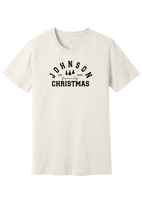 Personalized Family Christmas tee in Vintage White, featuring a personalized family last name arched over three pine trees with EST. and the year