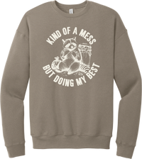 Kind of a Mess But Doing My Best crewneck sweatshirt in Tan, featuring a raccoon sitting beside a trash can with Kind of a mess but doing my best