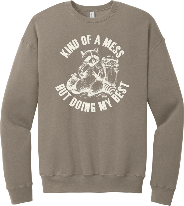 Kind of a Mess But Doing My Best crewneck sweatshirt in Tan, featuring a raccoon sitting beside a trash can with Kind of a mess but doing my best