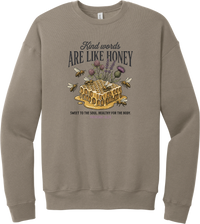 Words Like Honey crewneck sweatshirt in Tan, featuring a dripping honeycomb with bees and wildflowers under Kind Words Are Like Honey lettering and Proverbs 16:24